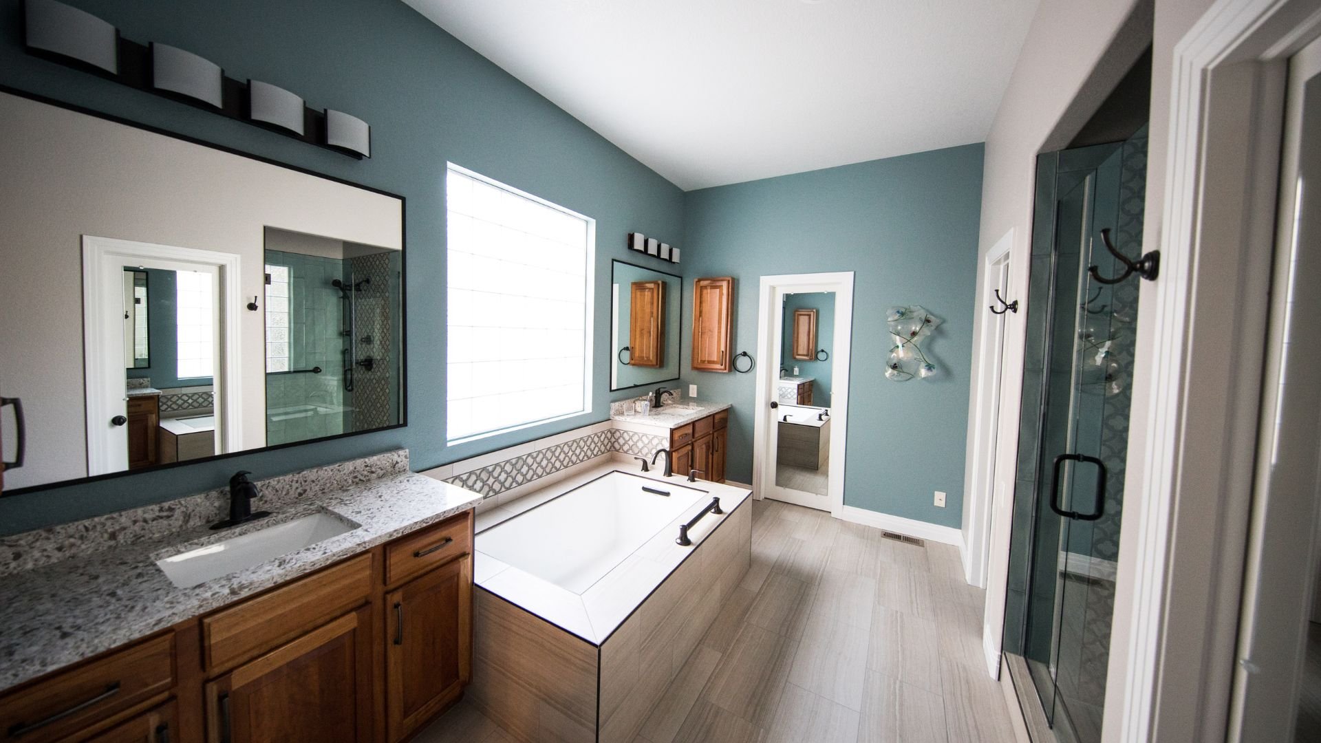 Modern bathroom with blue walls, wooden cabinets, and large bathtub