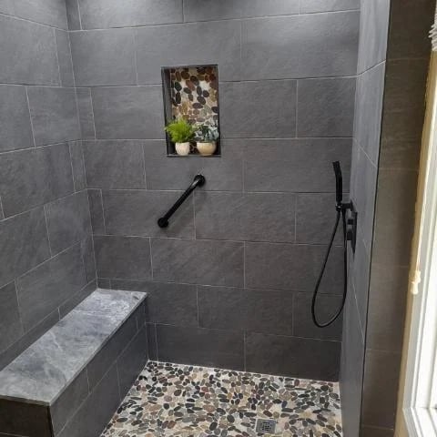 Modern gray tiled shower with stone accent niche and built-in bench