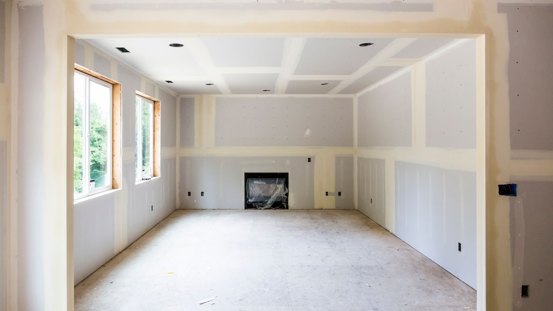 Unfinished room with drywall, windows, and a fireplace under construction