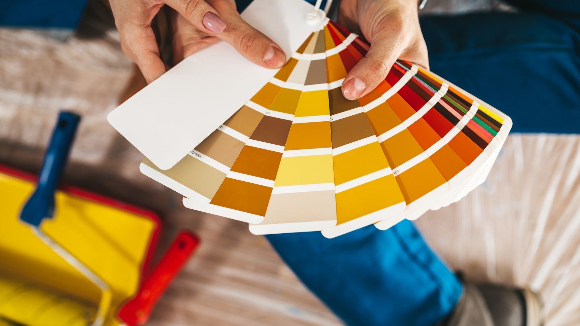 Hands holding a fan-shaped color palette with yellow and orange tones