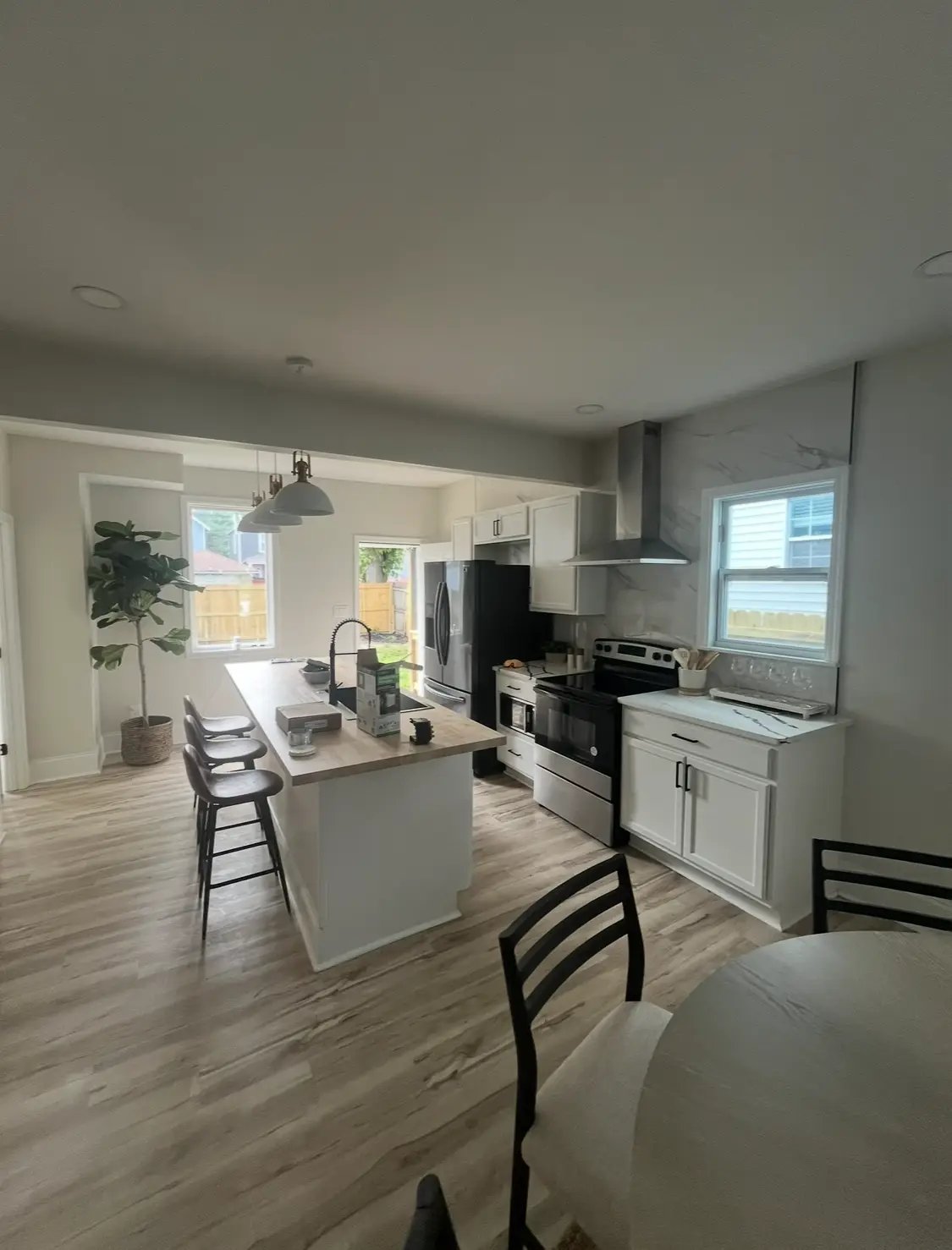 Modern white kitchen with island, bar stools, and stainless steel appliances