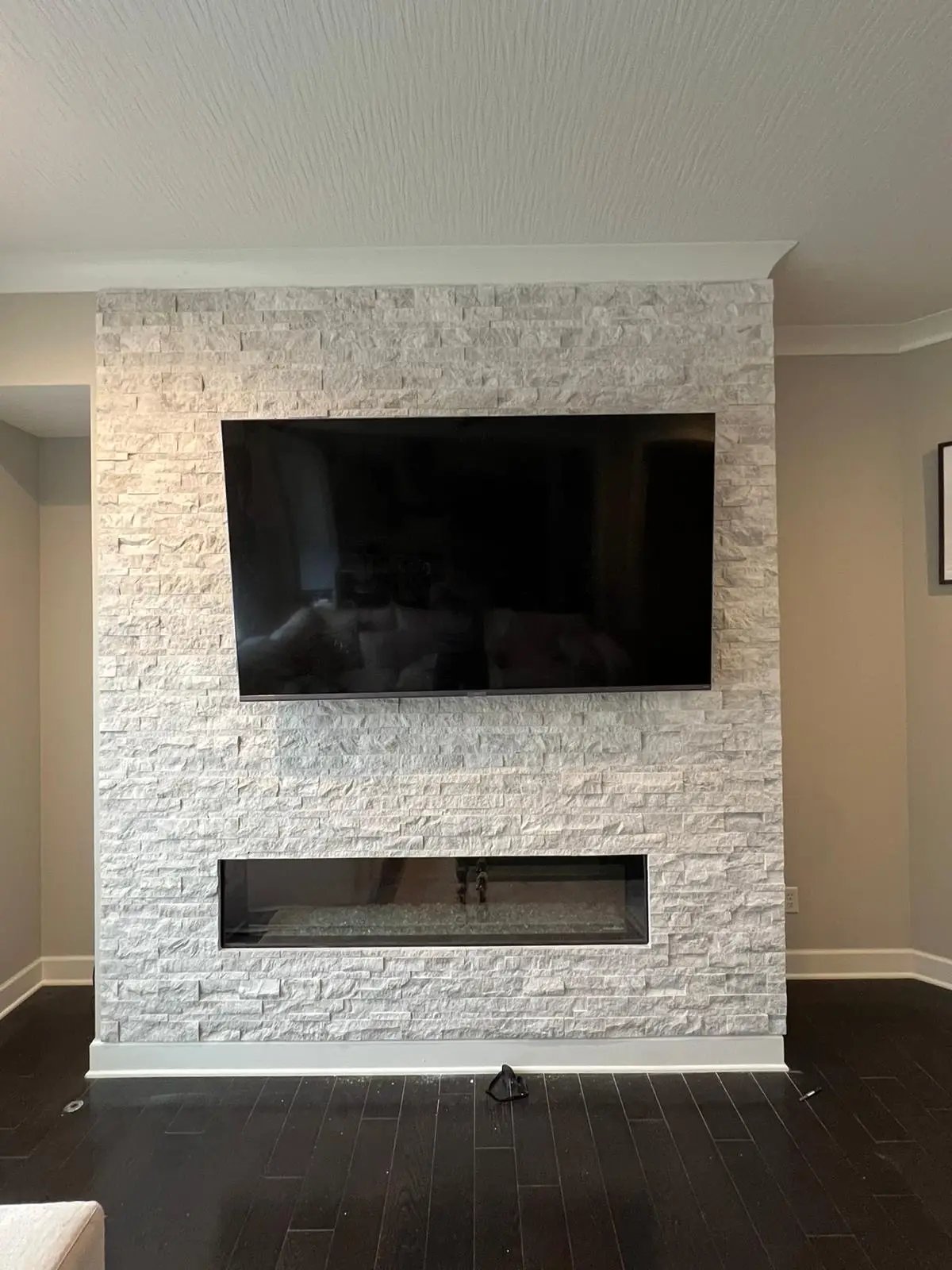 Modern white stone fireplace with mounted TV and linear gas fireplace