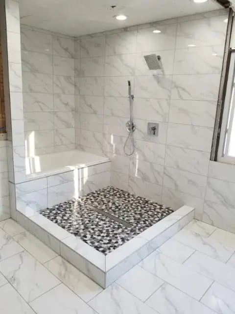 Modern marble shower with pebble floor and built-in bench