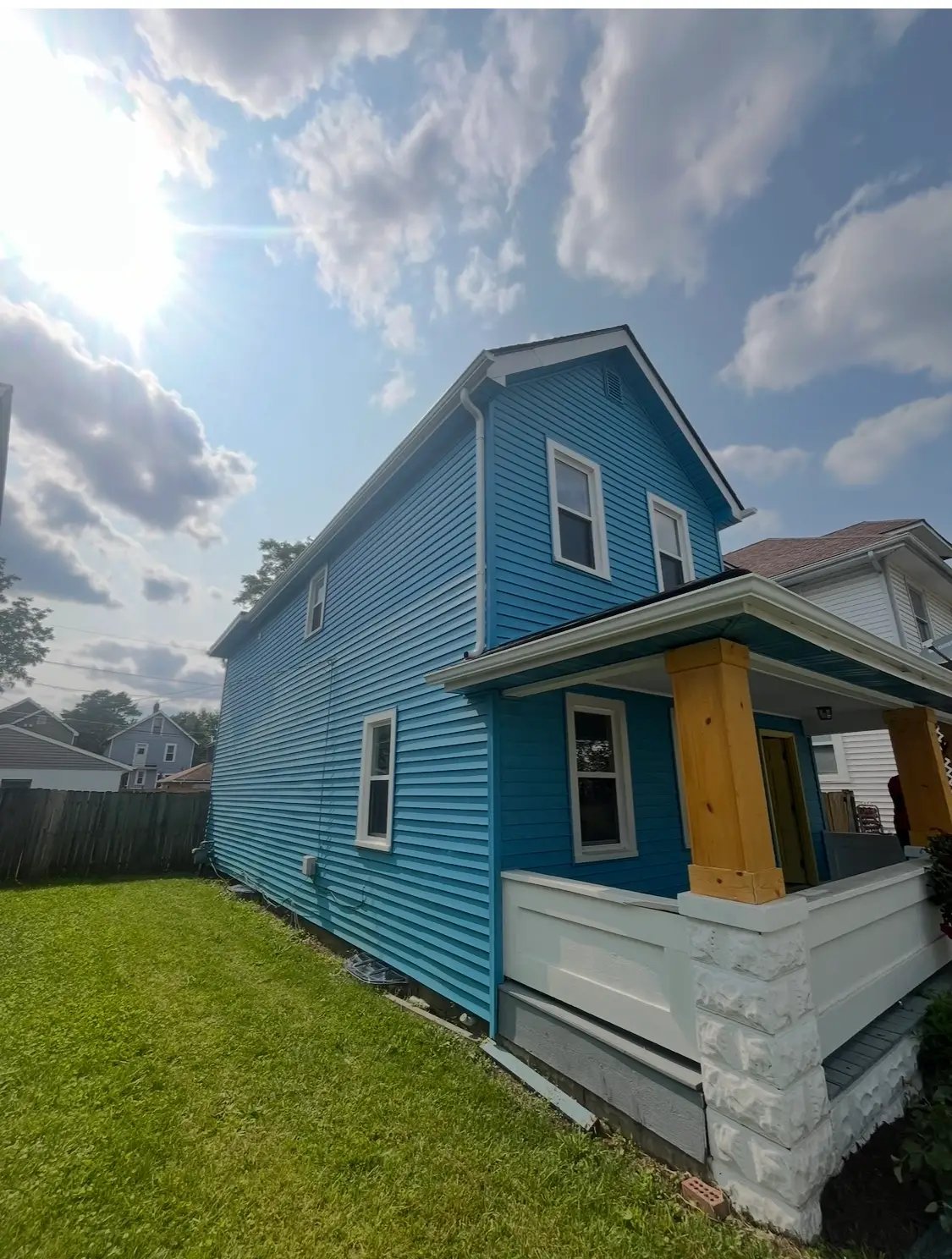 Blue two-story house with yellow porch column on sunny day
