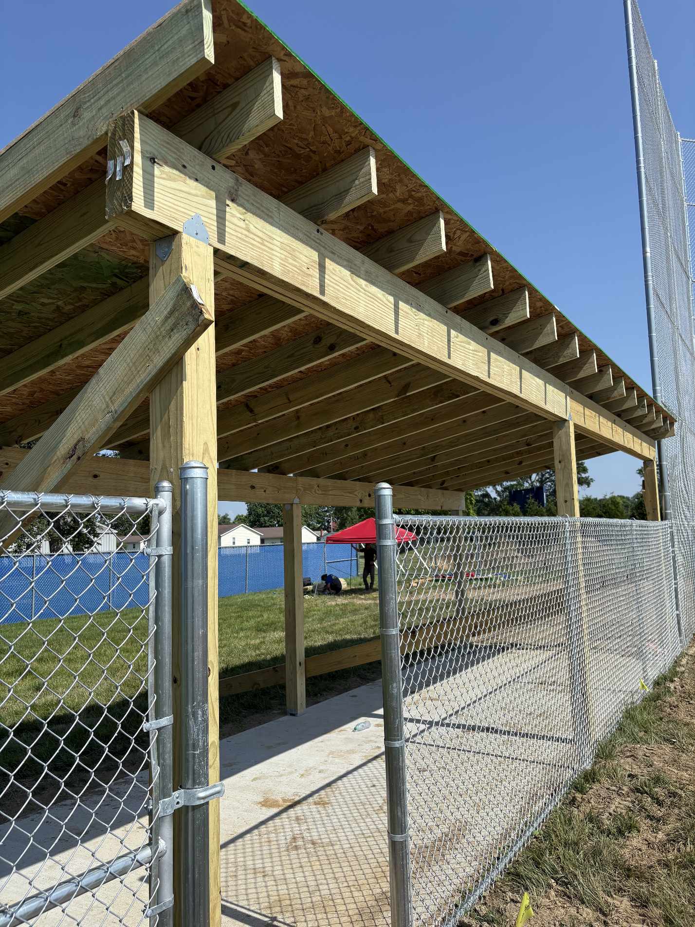 Wooden covered dugout with chain-link fence at outdoor sports field