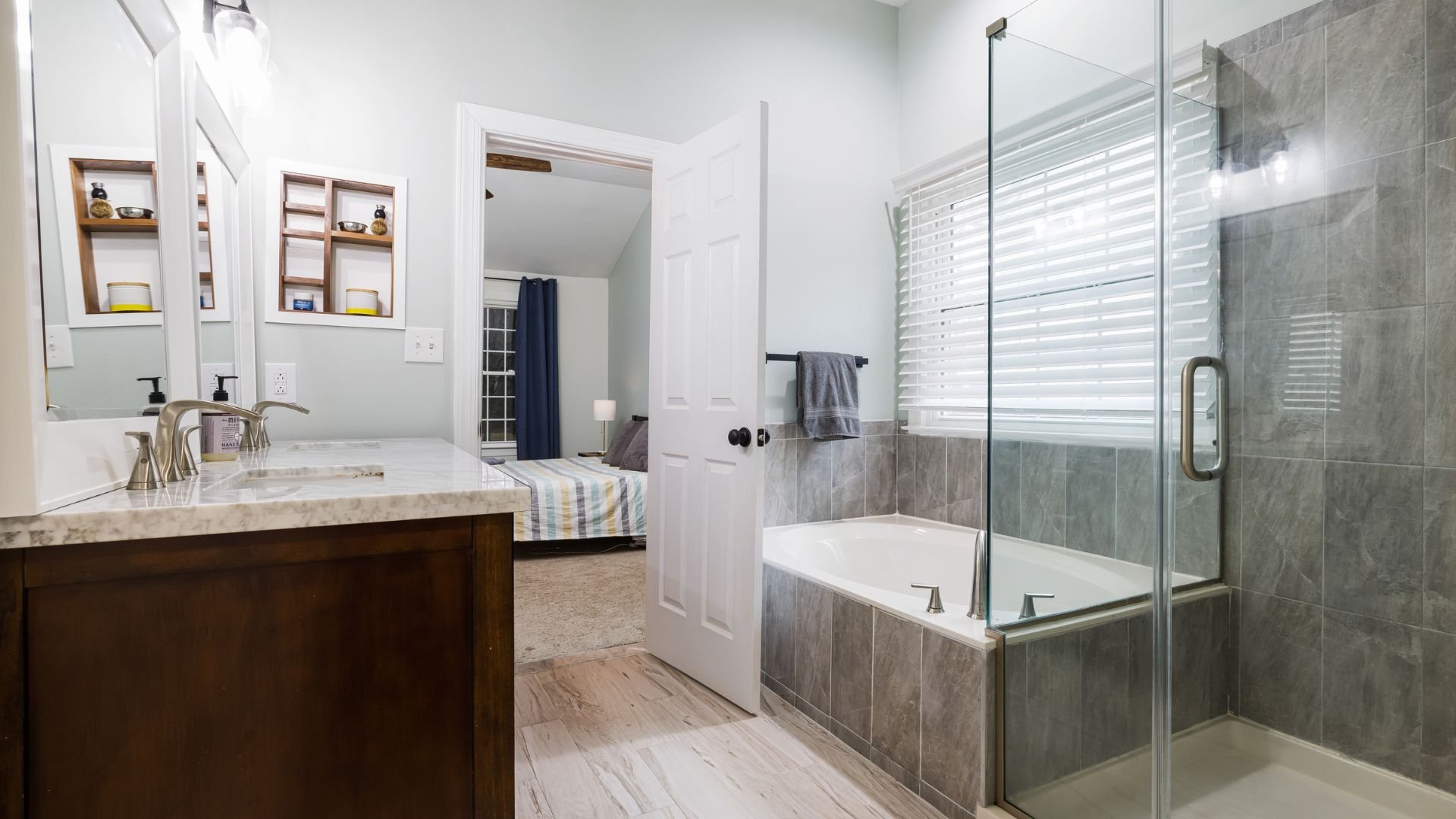 Modern bathroom with glass shower, wooden vanity, and white marble countertop