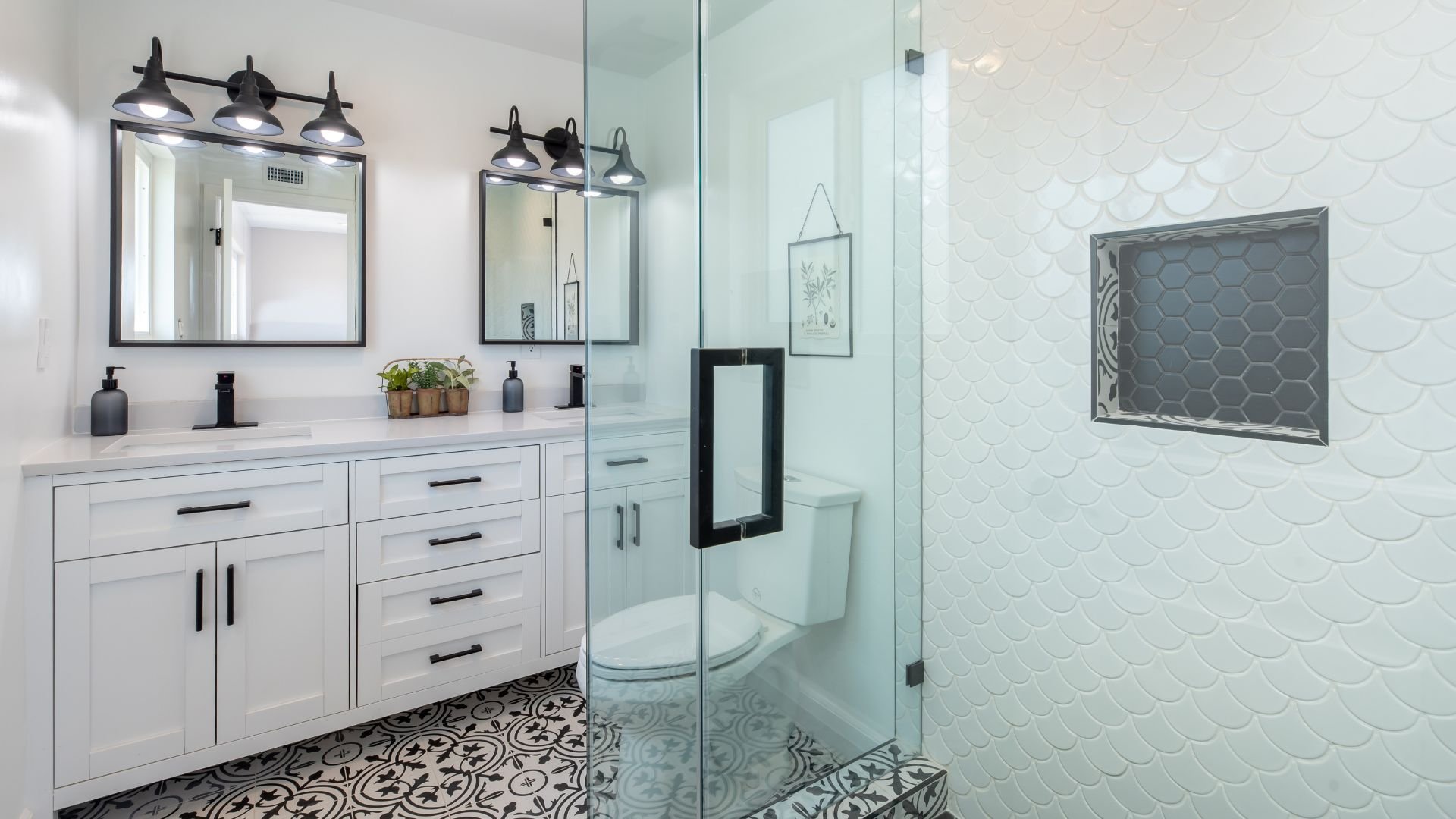 Modern white bathroom with glass shower, patterned floor, and black accents