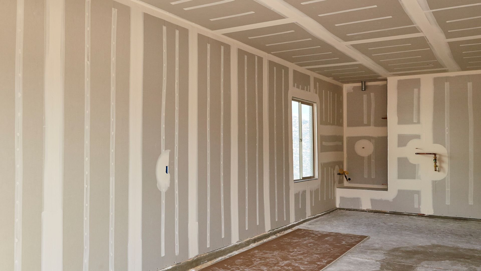 Unfinished room with drywall, window, and exposed construction details
