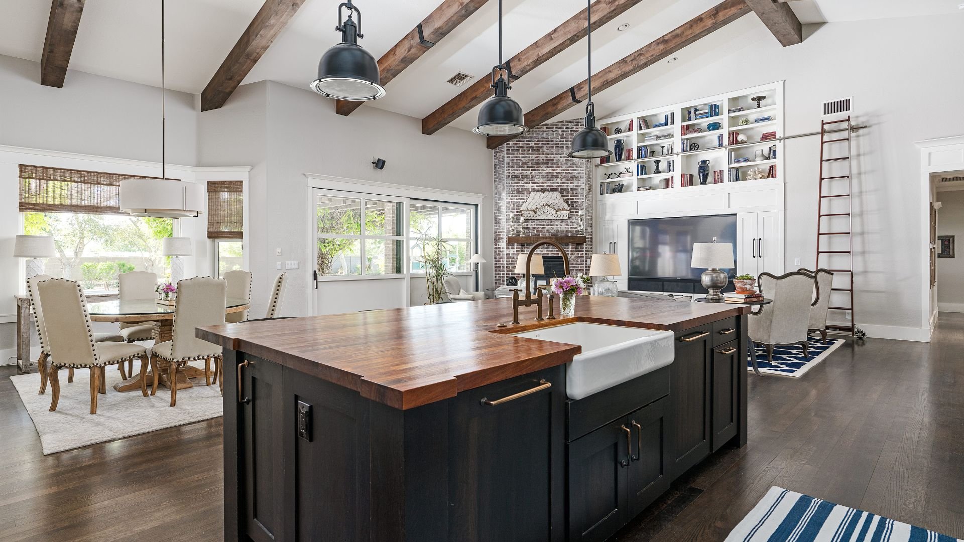 Modern farmhouse kitchen with wooden island, pendant lights, and bookshelf