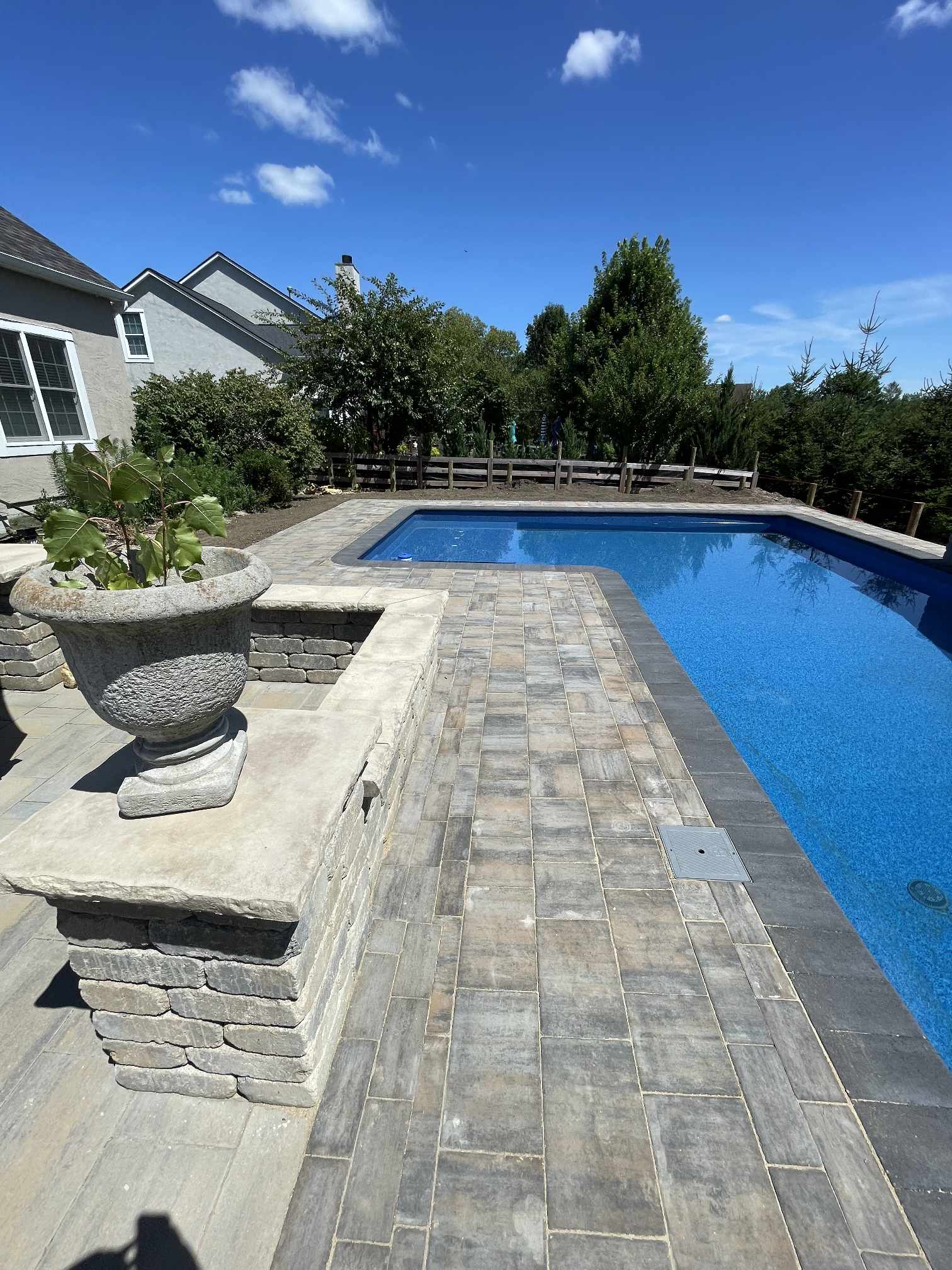 Backyard swimming pool with stone patio and landscaped surroundings