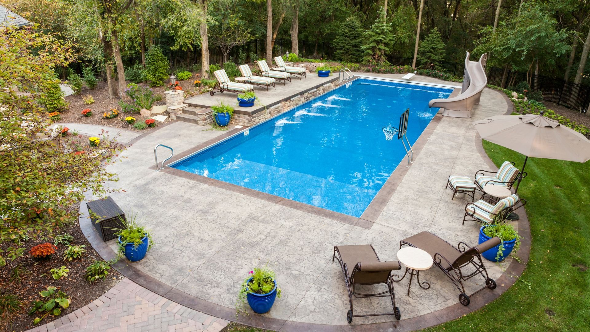 Backyard swimming pool with lounge chairs, slide, and landscaped garden