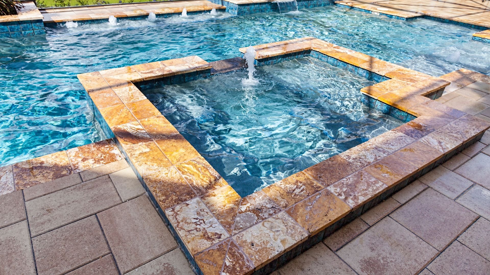Luxurious swimming pool with spa and water features, marble tile edges
